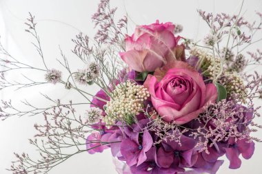 İki pembe gül buketi ve beyaz arkaplanda farklı mor ve beyaz çiçekler.