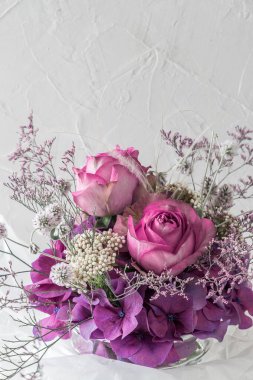 İki pembe gül buketi ve beyaz arkaplanda farklı mor ve beyaz çiçekler..