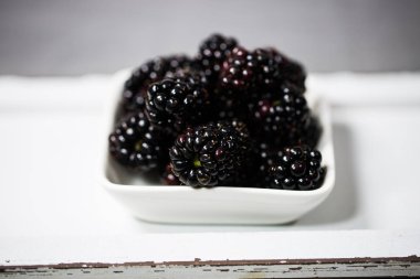 Bir kase, gri arka planda böğürtlen