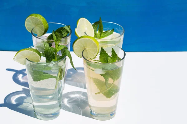 Limonade vor blauem Hintergrund, mit Minze und Limette — Stockfoto