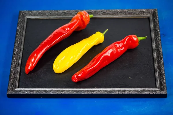 Chili pointu rouge et jaune sur tableau noir en ardoise — Photo