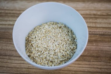 Bir beyaz Kupası, ahşap arka plan, diyet, yulaf ezmesi kuru