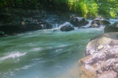 Siyah kayaların olduğu nehir ortada ve sağda ve solda yeşil bir çim var. Kelor nehri Yogyakarta Endonezya 'sında turistik bölgeler için çok uygun bir yer.