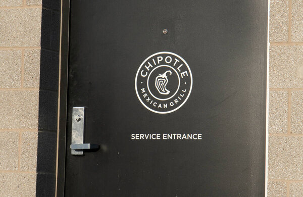 Иллинойс, США, - апрель 2020: Местный Chipotle открыт для мобильных заказов пикапов. Размещение клиентов с мобильными заказами с помощью либо без контактного диска через, или пешеходной зоны, которая имеет предопределенные пространства, чтобы стоять отмечены на земле до
 