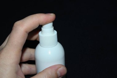 El, antiseptiğe siyah arka planda basar.