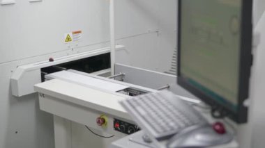 LED 'li tamamlanmış tahta, tamamlanmış ürün için taşıyıcı bant boyunca kutuya doğru hareket eder. Önplanda, bir üretim süreci kontrol terminali