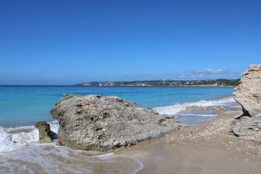 Sahilde ön planda kayalar var.