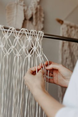 Kız makrome örüyor. Boho dekoru dokuma sürecinde. El yapımı.