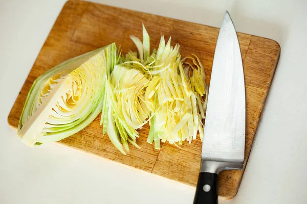 The cabbage is on the Board and there is a knife next to it. Cooking. Sliced cabbage for borscht