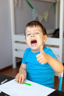 Yaratıcı çocuk, odasında resim yapıyor. Anaokulu çocukları için eğitici oyunlar