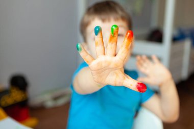 Yaratıcı çocuk, odasında resim yapıyor. Anaokulu çocukları için eğitici oyunlar. Ön planda bir çocuk eli