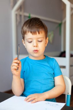 Yaratıcı çocuk, odasında resim yapıyor. Anaokulu çocukları için eğitici oyunlar