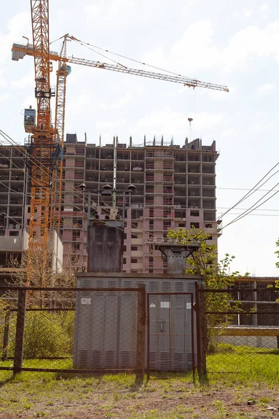 Transformer box on the background of the construction of a multi-storey residential building. Construction crane