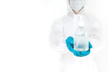 Koruyucu kıyafetli bir adam el dezenfeksiyonu için antibakteriyel antiseptik jel tutuyor. Grip salgını ve koronavirüs salgını sırasında sağlık hizmetlerinin önlenmesi