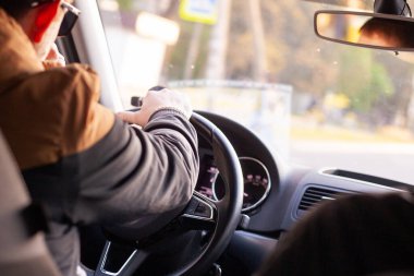 Adam sürüyor. Sürücü direksiyonu eliyle tutuyor..