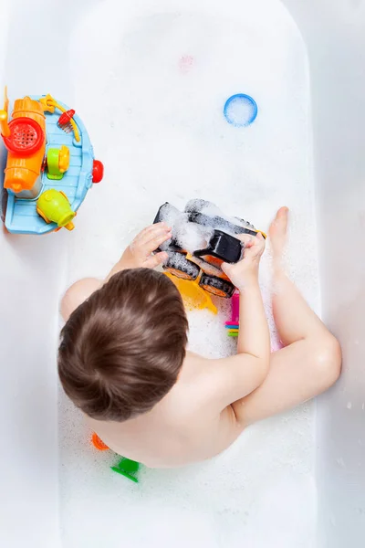 一个男孩在泡泡浴中洗澡 一个孩子在浴室里玩玩具 — 图库照片