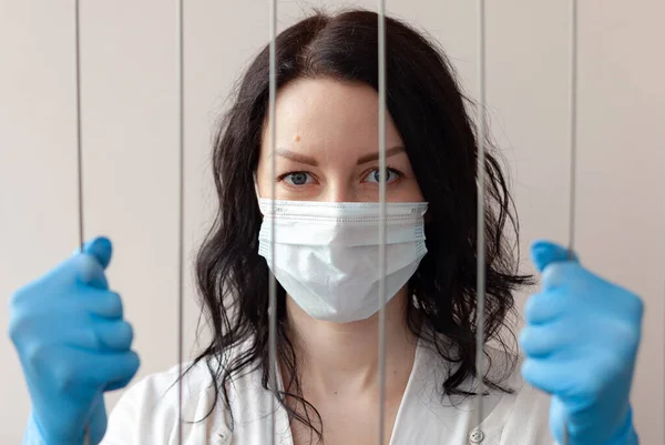 一个戴手套和防护面罩的女人紧紧抓住栅栏 用自我隔离的概念对抗头孢病毒 — 图库照片