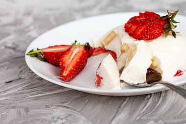 Taze çilekli İtalyan tatlı panna cotta ve gri beton arka planda muz.