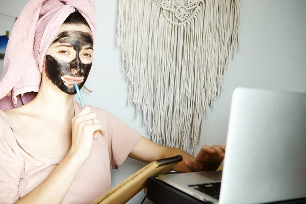 Młoda Kobieta Ręcznikiem Głowie Czarną Maską Gliny Siedząca Domu Używająca — Zdjęcie stockowe
