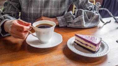 İşten sonra kahve içip kek yiyen bir kadın. ahşap masa