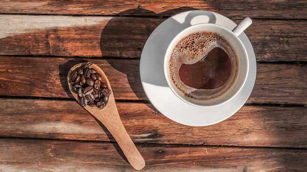 用白咖啡杯把黑咖啡豆贴在木制背景上 — 图库照片