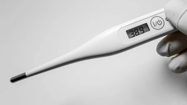 Beyaz arka planda beyaz dijital termometreyi tutan eller. Ateşi ve sağlık sigortası konsepti 38.9 C. 19 testini tamamla. Sağlık hizmetleri geçmişi. Bireysel solunum koruması.