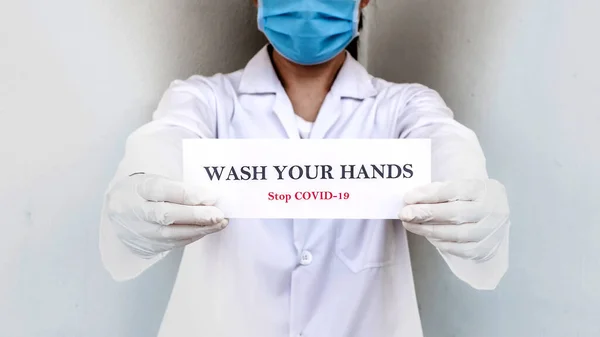 Bir doktor elinde Coronavirus ya da Covid-19 salgınından korumak için motive olmuş insanlara el işareti tutuyor.