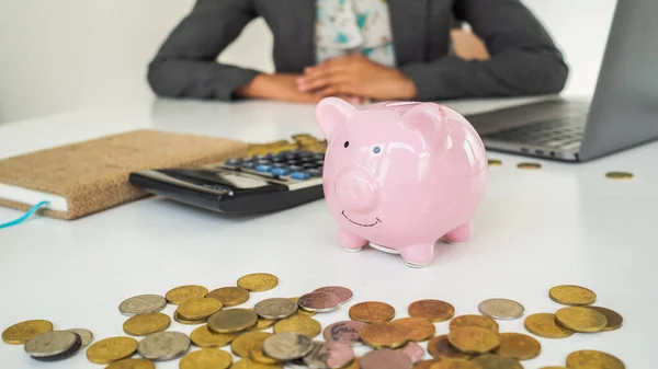 A pink piggy bank in office with successful business women is working background. saving money is investment. saving money for business investment.