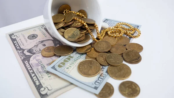 Bozuk paralar, altın ve banknotlar beyaz arka plandaki bardaktan dökülüyor. Bankacılık ve finansal konsept.
