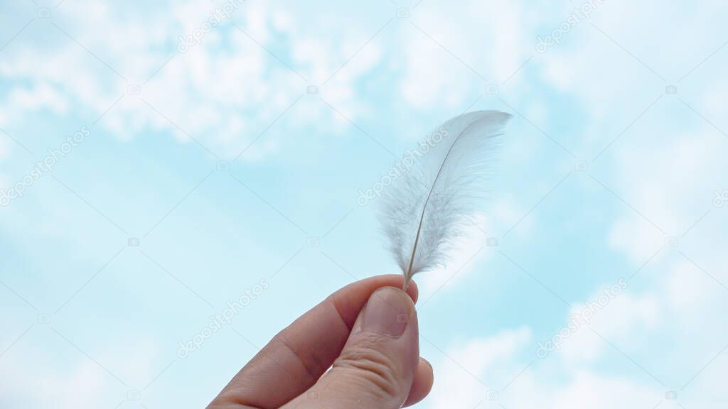 Bird feather in a hand in abstract groups of stratus clouds height in the sky. Stunning springtime weather. beautiful clouds footag