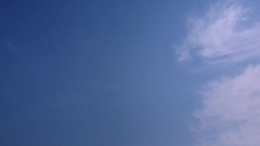 Mavi gökyüzünün sağ tarafında gündüz vakti yatay hareket eden beyaz ince bulutlar.. 