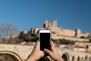 Ortaçağ şatosunun akıllı telefonuyla fotoğraf çeken genç bir turistin yakın çekimi..