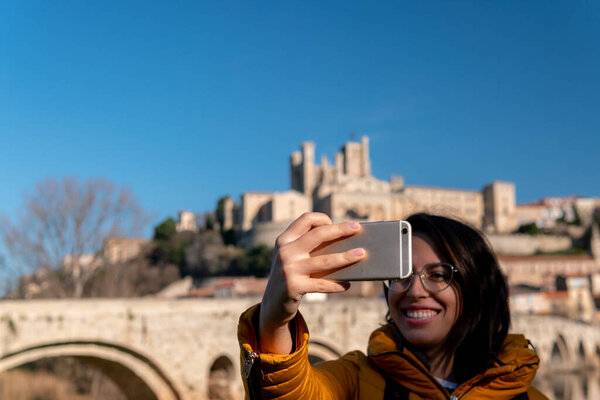 Молодой кавказский турист делает селфи со средневековым замком на заднем плане
