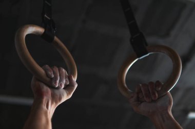 Spor yüzükleri tutan genç, kaslı bir sporcunun yakın çekimi.
