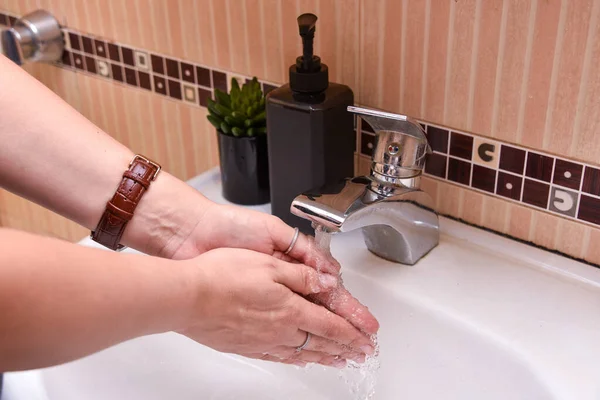 washing of hands with soup under running the water in the bathroom.