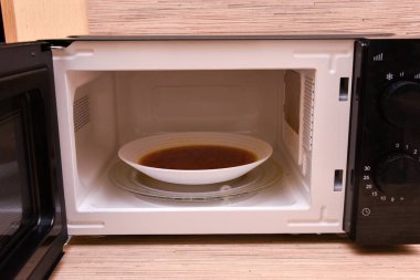 İçinde çorba olan mikrodalgayı aç. Mikrodalga fırının görüntüsü. Modern mikrodalga fırın evde.