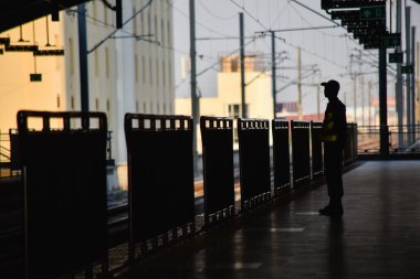 Şehrin arka planındaki metro istasyonunda bir polisin silueti..