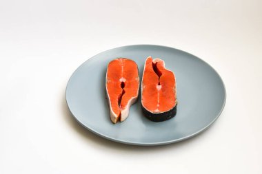 İki taze çiğ somon balığı bifteği tabakta, beyaz arka planda izole edilmiş..