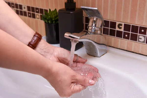 washing of hands with soup under running the water in the bathroom.