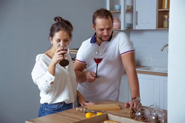 man and girl in the kitchen, eat pizza, drink wine and laugh merrily