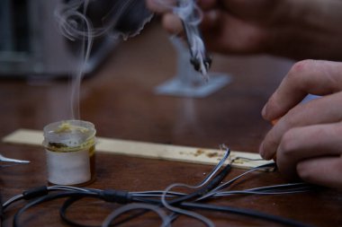 Bir adam kaynak makinesiyle çalışır, elektroniği tamir eder.