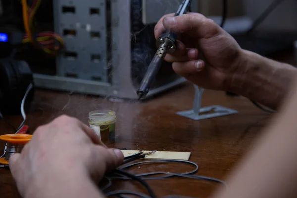 a man works with a blowtorch, repairs electronics