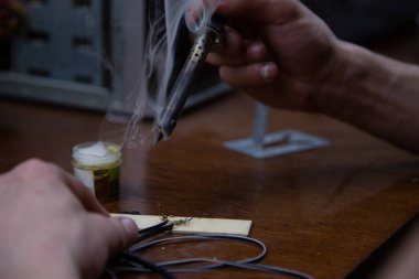 Bir adam kaynak makinesiyle çalışır, elektroniği tamir eder.