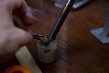 Bir adam kaynak makinesiyle çalışır, elektroniği tamir eder.