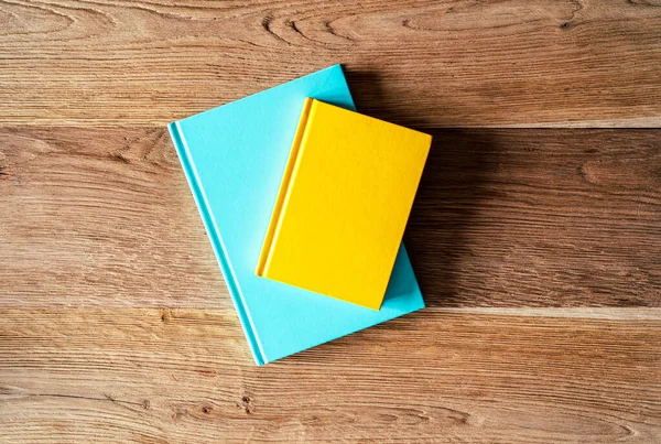 İki renkli defter mavi nane yeşili ve sarı ahşap arka planda.
