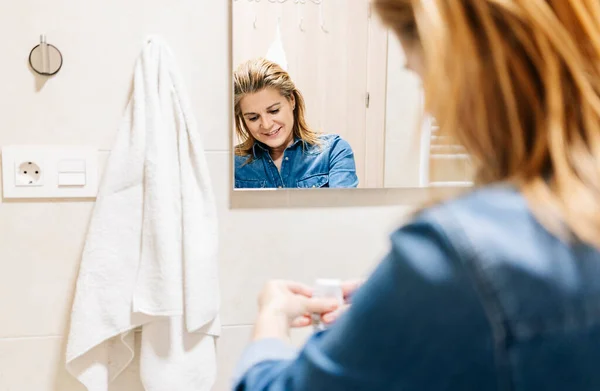 Una mujer se tiñe el pelo en casa . — Foto de Stock