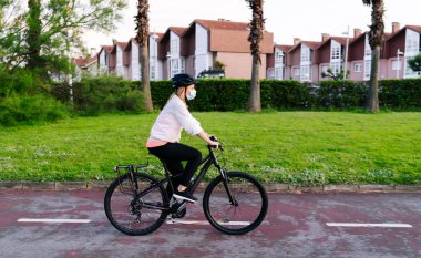 Yüzünde güvenlik maskesi olan bisikletli bir kadın.