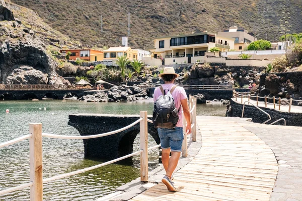 A tourist with a hat and backpack by a coastal town El Hierro, Canary Islands Royalty Free Stock Images