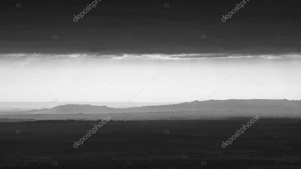 Telephoto view of the hills in the distance, covered by a fog.  Monochrome image from the Malvern Hills, UK