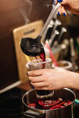 Kız sıcak sıcak şarabı bardaklara dolduruyor. Bardakların kenarları şekerle kaplıdır..